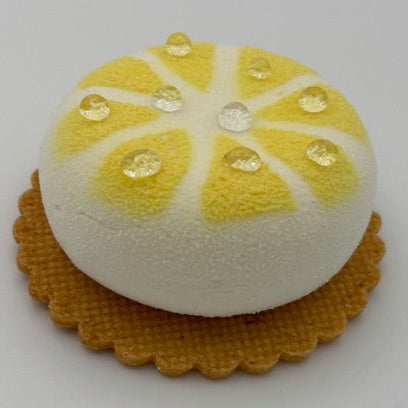A refined individual citrus dessert featuring a glossy velvet cocoa glaze. The interior reveals layers of citrus jam, light lemon sponge, and airy citrus mousse, all resting on a crisp lemon sable base