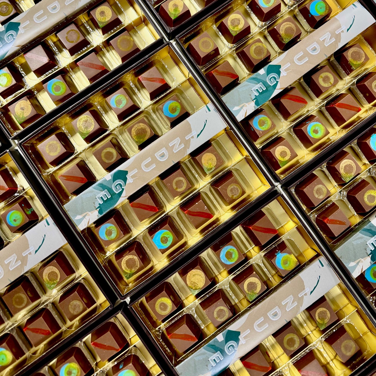 Multiple boxes of chocolate with decorative labels on a grid pattern