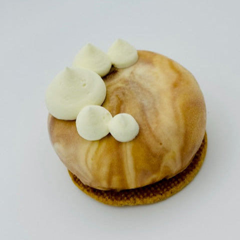 "Individual dessert featuring a sticky toffee pudding base, topped with Irish cream liqueur mousse and finished with a marbled milk and dark chocolate glaze, set on a crisp sablé biscuit.