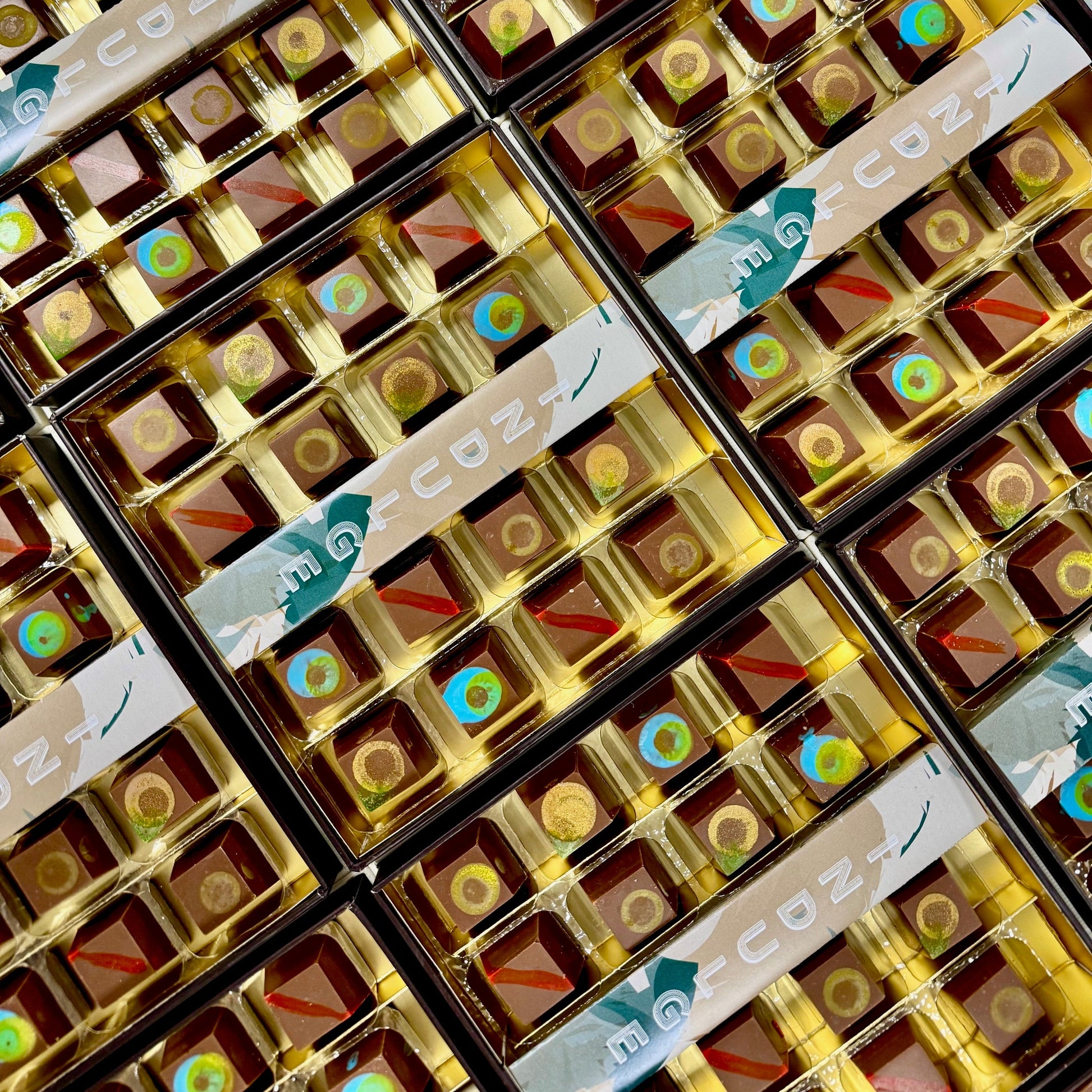 Multiple boxes of chocolate with decorative labels on a grid pattern
