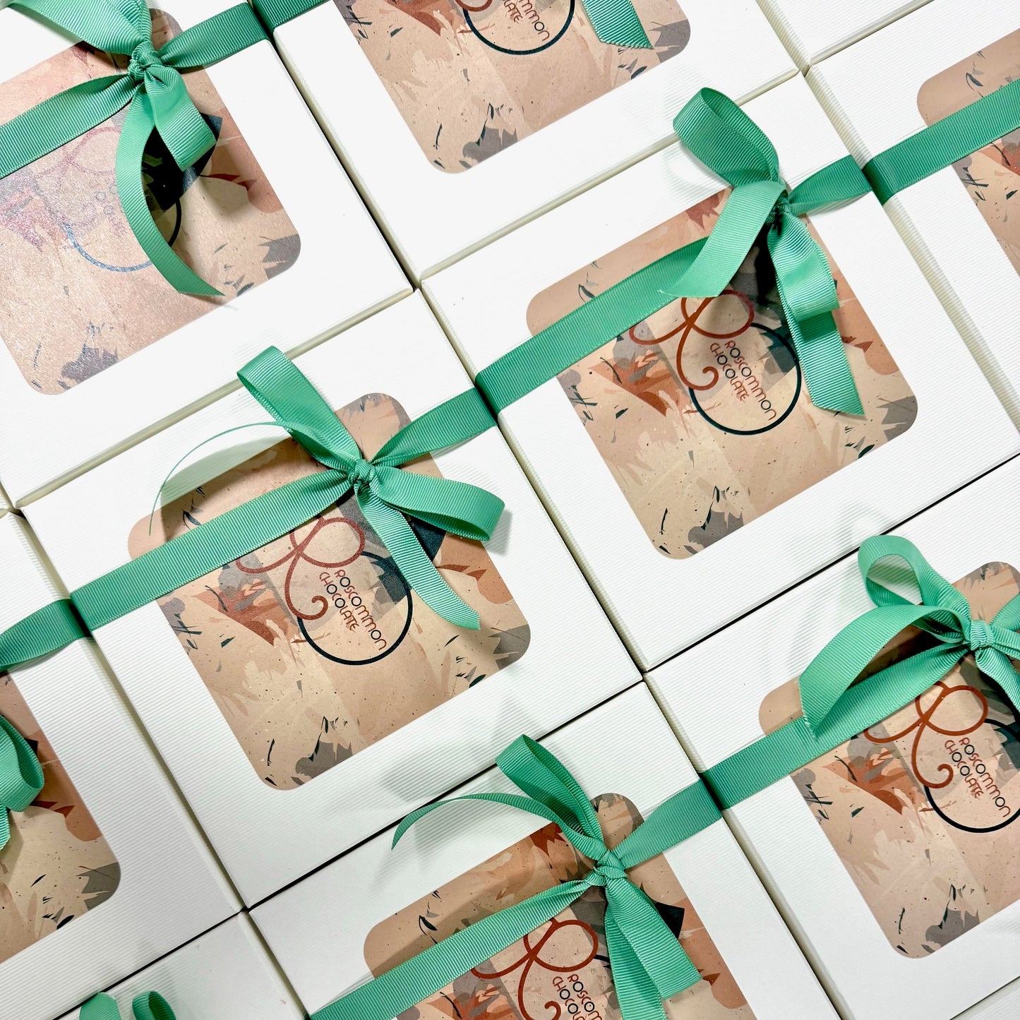 Gift boxes with green ribbons arranged on a tiled surface
