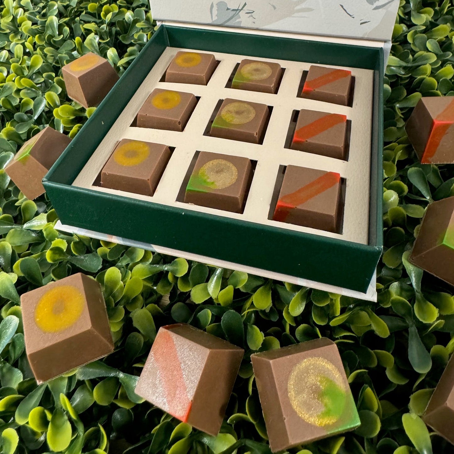 Box of chocolates with a decorative cover on a green leafy background